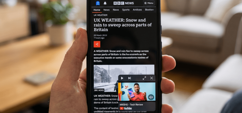 Smartphone displaying BBC News article about UK weather with snow and rain forecast